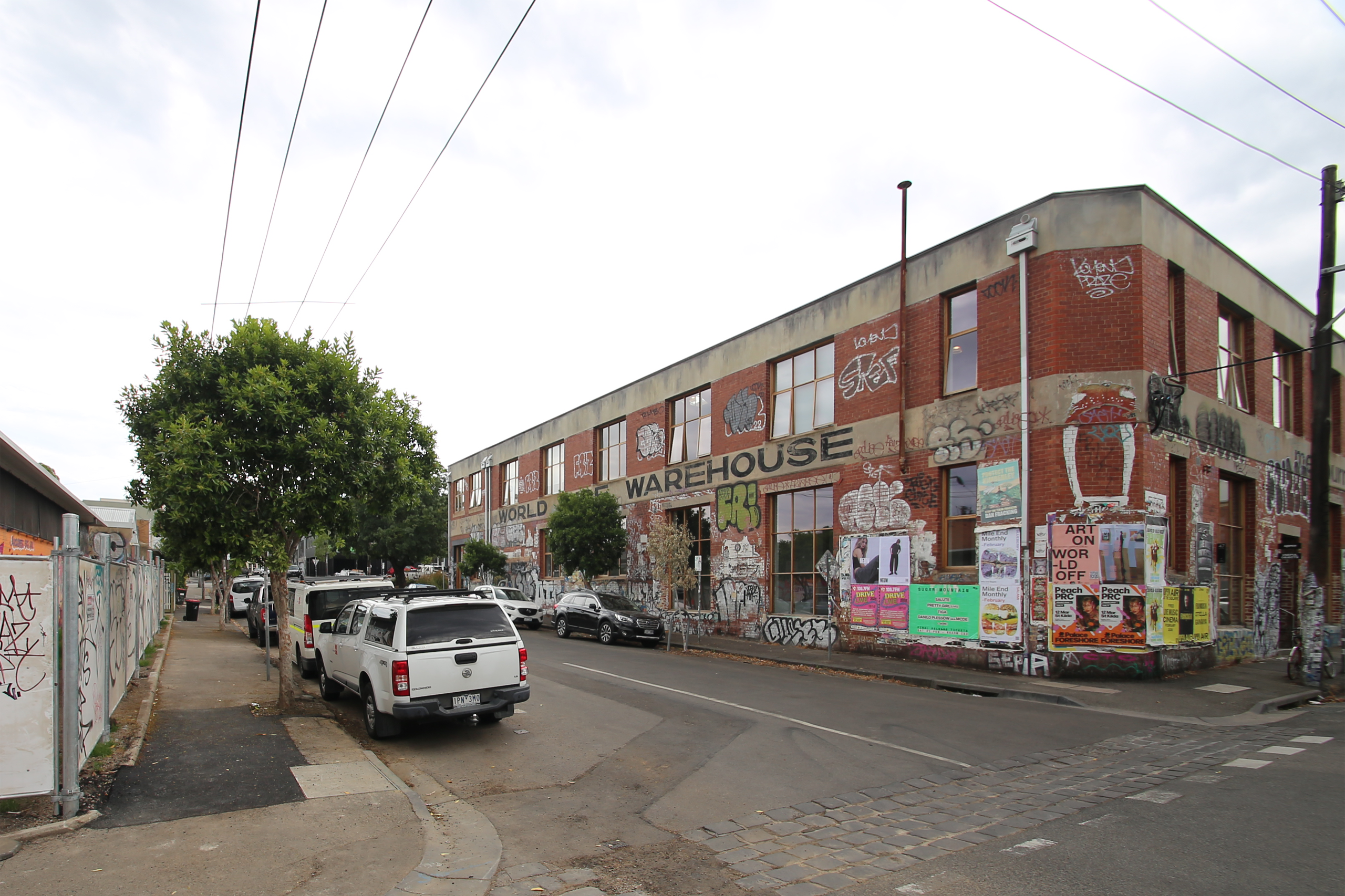 Before: A street with parked cars and a red brick building